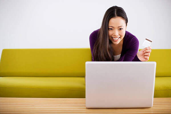 Smiling woman sitting on a yellow couch viewing a laptop