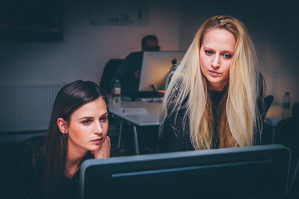 Image of two women looking at a desktop monitor in an office